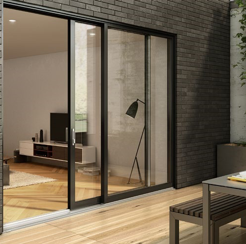 Sliding glass doors open to a modern living room with a TV and lamp, surrounded by a brick wall.